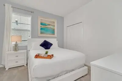 a white bedroom with a white bed and a window at Serene Sunsets Villa - E04 in Kissimmee