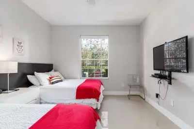 two beds in a white room with a tv at Mickey Mouse #104 in Orlando