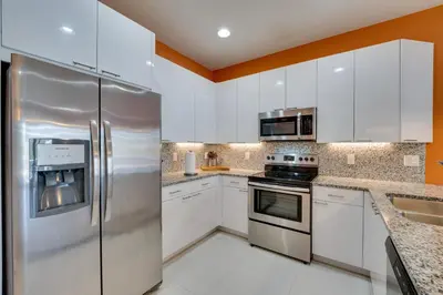a kitchen with white cabinets and stainless steel appliances at Townhome with Lanai about 9 Mi to Disney! in Orlando