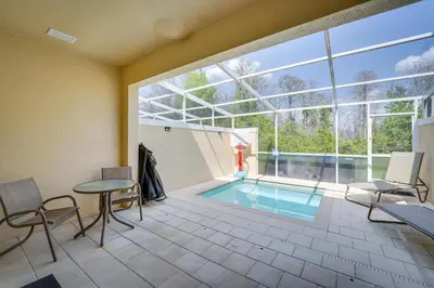 a swimming pool with chairs and a table in a room at Townhome with Lanai about 9 Mi to Disney! in Orlando