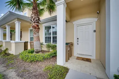 a house with a palm tree and a white door at Townhome with Lanai about 9 Mi to Disney! in Orlando