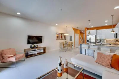 a living room with a white couch and a kitchen at Townhome with Lanai about 9 Mi to Disney! in Orlando