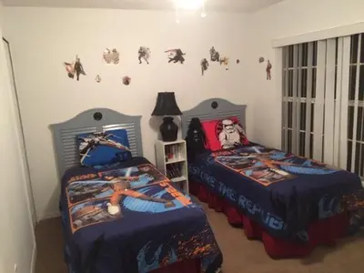 a bedroom with two beds and a wall with superhero decals at Florida Escape in Orlando