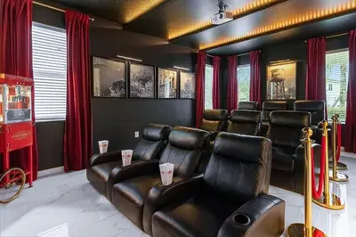 a cinema room with leather chairs and red curtains at 5BR Family Home with Pool & Hot Tub Near Disney in Kissimmee