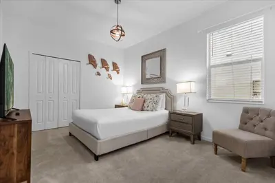 a white bedroom with a bed and a chair at 5BR Family Home with Pool & Hot Tub Near Disney in Kissimmee