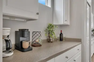 a kitchen counter with a coffee maker and a bottle of wine at 6 Bedroom Luxury Pool Home, Ensuite Bathrooms in Kissimmee