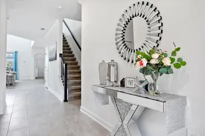 a hallway with a mirror and a vase of flowers on a counter at Modern Resort House Pool Wi-Fi Minutes to Disney in Kissimmee