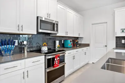 a kitchen with white cabinets and a stove top oven at Modern Resort House Pool Wi-Fi Minutes to Disney in Kissimmee