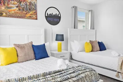 a bedroom with two white beds with colorful pillows at Modern Resort House Pool Wi-Fi Minutes to Disney in Kissimmee