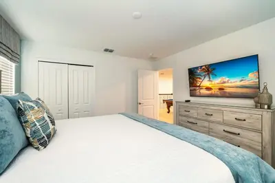 a bedroom with a large bed with a television on the wall at Amazing 8br villa w theme rms game room theater in Kissimmee
