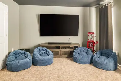 a living room with three blue chairs and a television at Awesome new 8br w theme rooms theater by Disney in Kissimmee