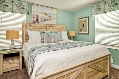 a bedroom with a large bed and two windows at Awesome new 8br w theme rooms theater by Disney in Kissimmee