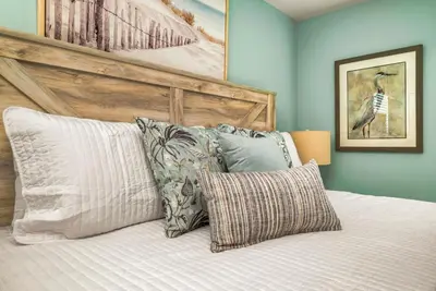 a bedroom with a bed with a wooden headboard and pillows at Awesome new 8br w theme rooms theater by Disney in Kissimmee