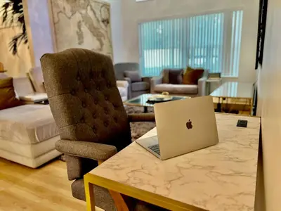 a living room with a table with a laptop on it at Luxury Home, Workspace, Movie Room and BBQ in Kissimmee