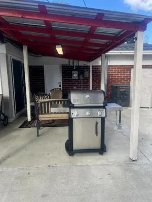 a grill sitting under a roof on a patio at Luxury Home, Workspace, Movie Room and BBQ in Kissimmee