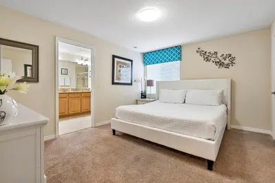 a bedroom with a white bed and a bathroom at Amazing 5BD and 4BH 6 miles from Disney in Kissimmee