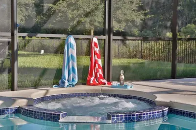 two closed umbrellas sitting next to a swimming pool at Large Pool Deck * All Rooms w/ Private Bathroom in Kissimmee