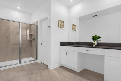 a white bathroom with a shower and a sink at Stylish Resort Villa w Pool Near Disney Gated 5BR in Kissimmee
