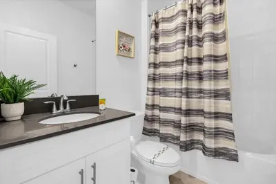 a bathroom with a sink and a toilet and a shower curtain at Stylish Resort Villa w Pool Near Disney Gated 5BR in Kissimmee
