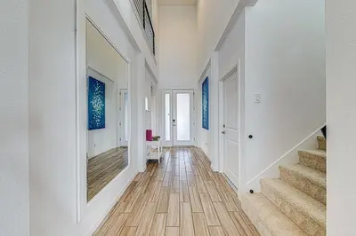 a hallway with white walls and wooden floors and stairs at #371-Stunning 6 bed with modern decor, south facing pool and spa overlooking water in Kissimmee
