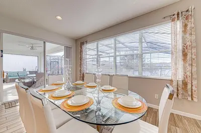 a dining room with a glass table and chairs at #371-Stunning 6 bed with modern decor, south facing pool and spa overlooking water in Kissimmee