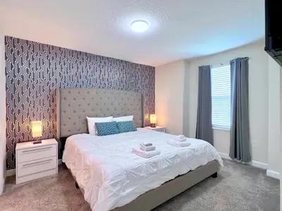 a bedroom with a large bed and two night stands with lamps at Eight-Bedroom House in Kissimmee