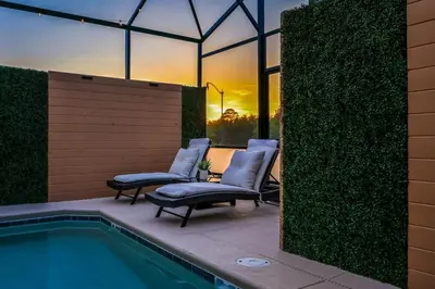 a patio with two chairs next to a swimming pool at Brand New Corner Lot Pond View Vacation Home in Kissimmee