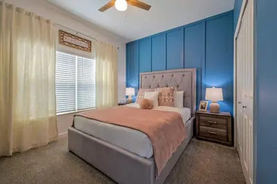 a bedroom with a large bed with blue walls at Brand New Corner Lot Pond View Vacation Home in Kissimmee