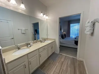 a bathroom with a sink and a mirror and a bed at #372-Welcome to Lightwater Villa, your Modern Disney Vacation home! South-Facing Pool & Spa Overlooking Lake in Kissimmee