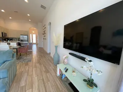 a living room with a large flat screen tv on a wall at #372-Welcome to Lightwater Villa, your Modern Disney Vacation home! South-Facing Pool & Spa Overlooking Lake in Kissimmee