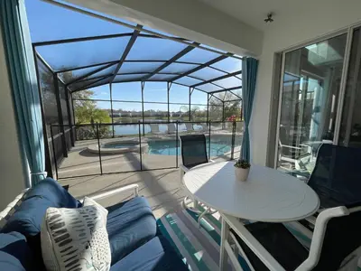 a living room with a table and a view of a pool at #372-Welcome to Lightwater Villa, your Modern Disney Vacation home! South-Facing Pool & Spa Overlooking Lake in Kissimmee