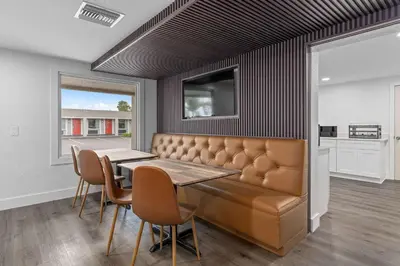 a dining room with a bench and a table and chairs at Travelodge by Wyndham Kissimmee Orlando in Kissimmee