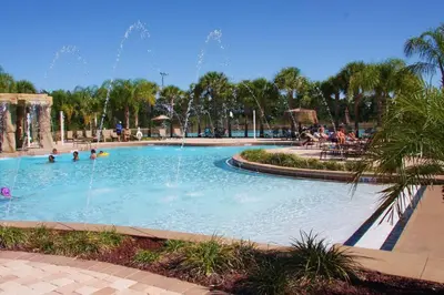 a pool at a resort with people in it at Spacious 4 bed 3 bath Townhome with pool 5 STARS!! in Kissimmee