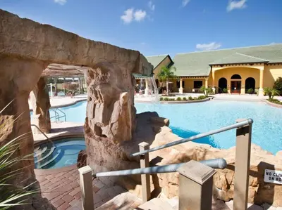 a pool in a resort with a rock wall at Spacious 4 bed 3 bath Townhome with pool 5 STARS!! in Kissimmee