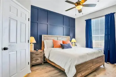 a bedroom with blue walls and a bed with orange pillows at Mickey's Hideaway Windsor Hills Resort in Orlando