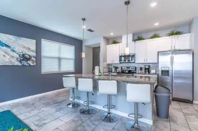 a kitchen with white cabinets and a counter with stools at 5134 Compass Bay in Kissimmee