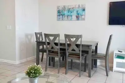 a dining room table with four chairs and a television at Minutes to Disney, Free Water Park & Private Pool in Orlando