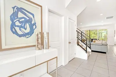 a living room with white walls and a staircase at Modern 6BR Home - Pool BBQ Hot Tub - Near Disney in Kissimmee