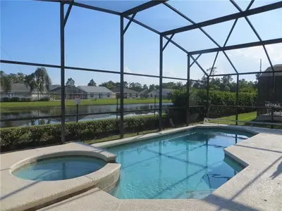 a large swimming pool with a metal structure at #463-Fabulous 4 bed villa with south facing private pool and spa overlooking water in Kissimmee