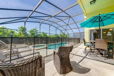 a patio with chairs and an umbrella and a pool at #463-Fabulous 4 bed villa with south facing private pool and spa overlooking water in Kissimmee