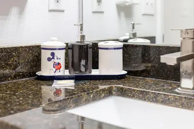 a bathroom counter with two soap dispensers and a sink at #463-Fabulous 4 bed villa with south facing private pool and spa overlooking water in Kissimmee