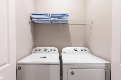 a small laundry room with two white appliances and towels at Gorgeous New 4 Beds DREAM Villa 5 min to Disney in Orlando