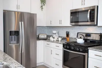 a kitchen with white cabinets and a stainless steel refrigerator at Dreamscape NEW 4 Suites Villa 5 min to Disney in Orlando