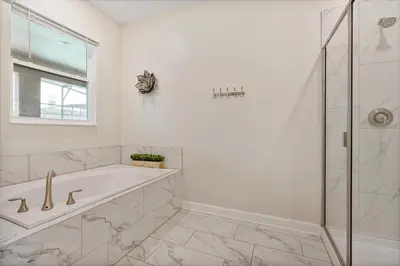 a white bathroom with a tub and a glass shower at New Home 9Bedrooms e 5Bath At Storey Lake in Kissimmee
