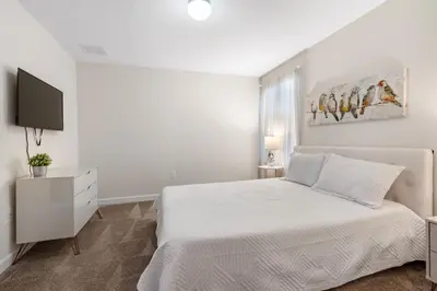 a white bedroom with a bed and a tv at New Home 9Bedrooms e 5Bath At Storey Lake in Kissimmee