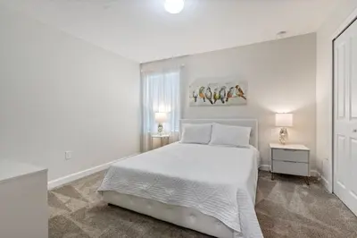 a white bedroom with a bed and a window at New Home 9Bedrooms e 5Bath At Storey Lake in Kissimmee