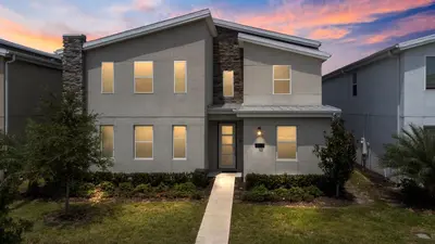 a gray house with a sunset in the background at New Home 9Bedrooms e 5Bath At Storey Lake in Kissimmee