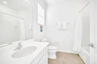 a white bathroom with a sink and a toilet at 10BR Resort Home - Pool Hot tub Games - Near Disney in Kissimmee