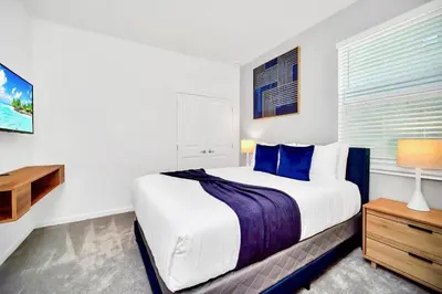 a white bedroom with a large bed and a window at 10BR Resort Home - Pool Hot tub Games - Near Disney in Kissimmee