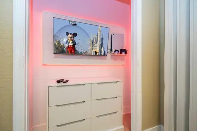 a childs room with a pink wall with a picture of a mickey mouse at Incredible Condo - 5 Min to Disney Windsor Hills in Orlando